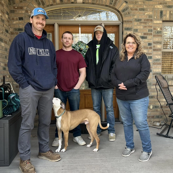 A family with a golden retriever poses for a photo with home movers.