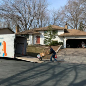 A mover using a utility dolly to load boxes into a trailer.