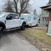 A truck and moving trailer parked in front of a house.