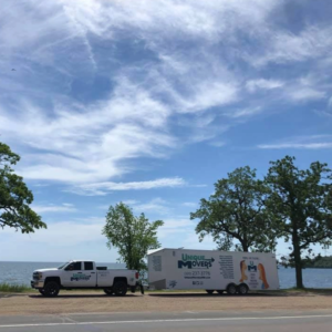 A moving truck and trailer on the road for a move.