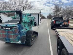 Unique Movers skid loader carrying a small chicken coop