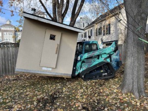 Unique Movers skid loader moving a small shed