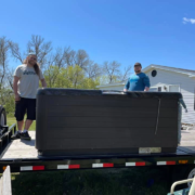 The Unique Movers team straps down a hot tub on a moving trailer.