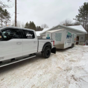 A moving truck and trailer parked in front of a home.