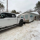 A moving truck and trailer parked in front of a home.
