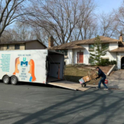 A mover loads items onto a moving trailer at a house.