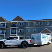 A moving truck and trailer outside of a senior living facility.