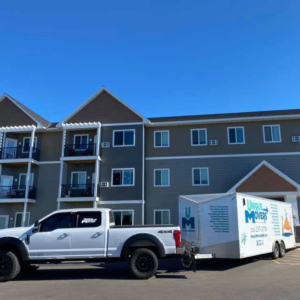 A moving truck and trailer outside of a senior living facility.
