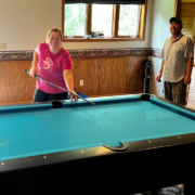 Pool table movers posing with a pool table at a customer’s home.