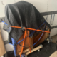 A piano wrapped up and strapped in on a moving trailer.